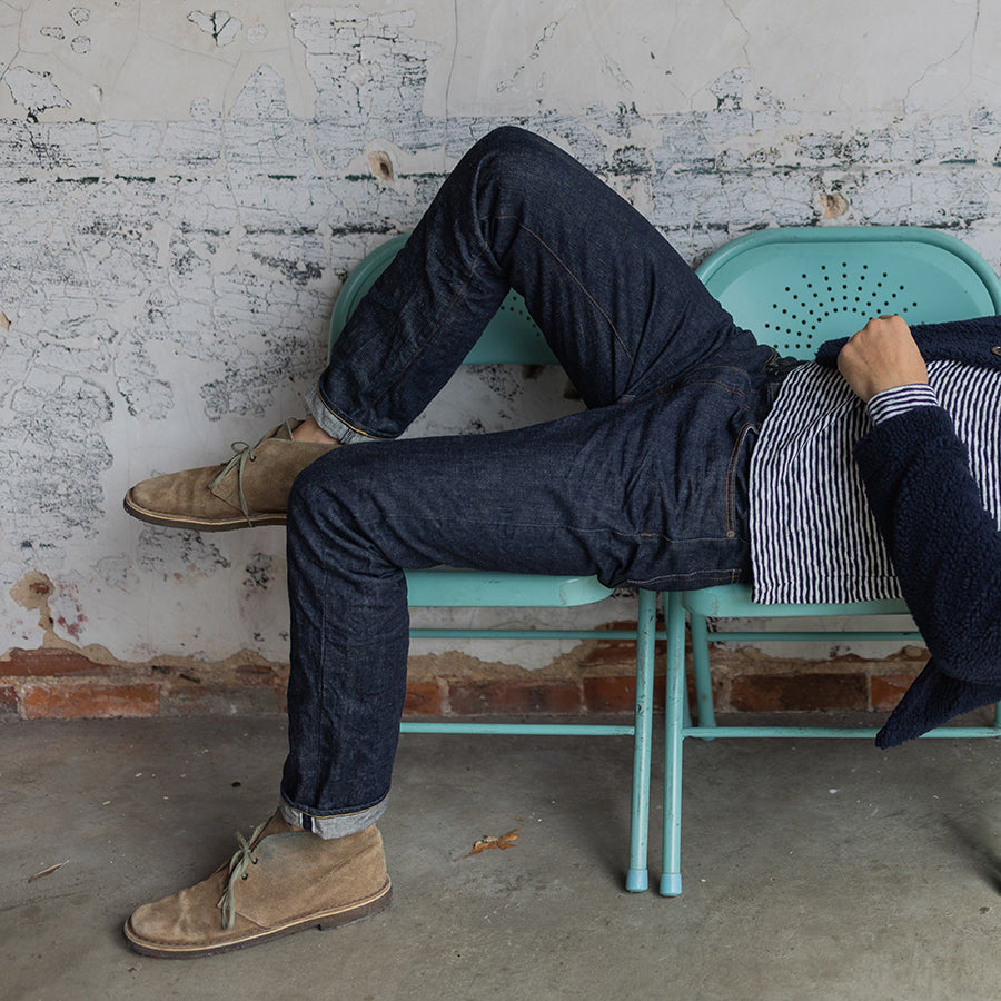 man wearing jeans by oobe brand laying on a chair