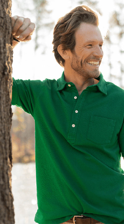 A man leaning against a tree outside wearing the OOBE Brand Avendon Pocket Polo in Kelly Green.