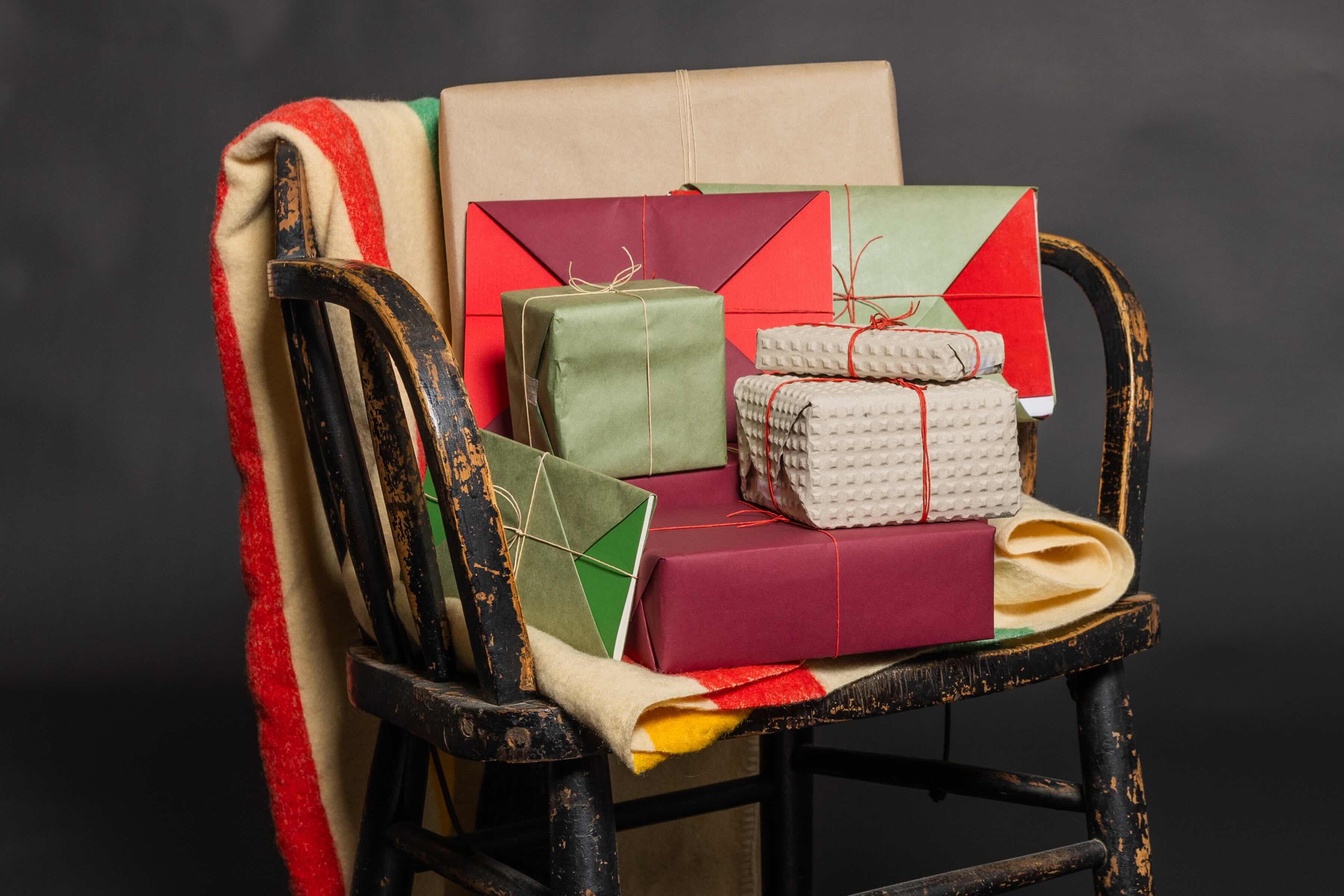 Stack of wrapped gifts on a colorful chair against a dark background