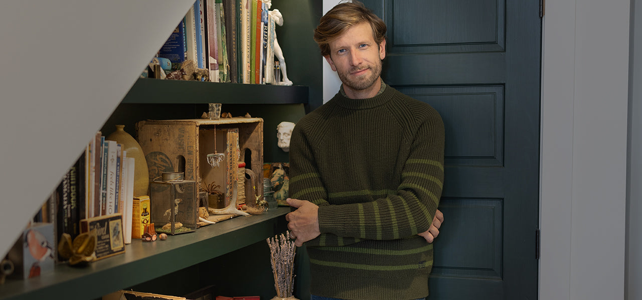 man standing by a shelf wearing a sweater
