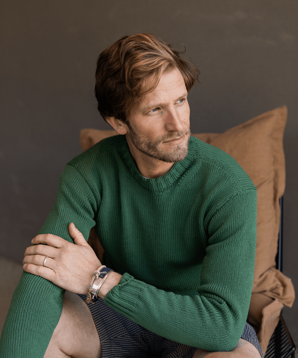 man sitting wearing a green lightweight sweater by oobe brand