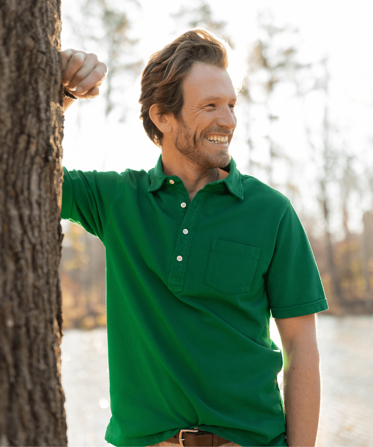 man standing by a tree wearing an oobe brand green polo shirt